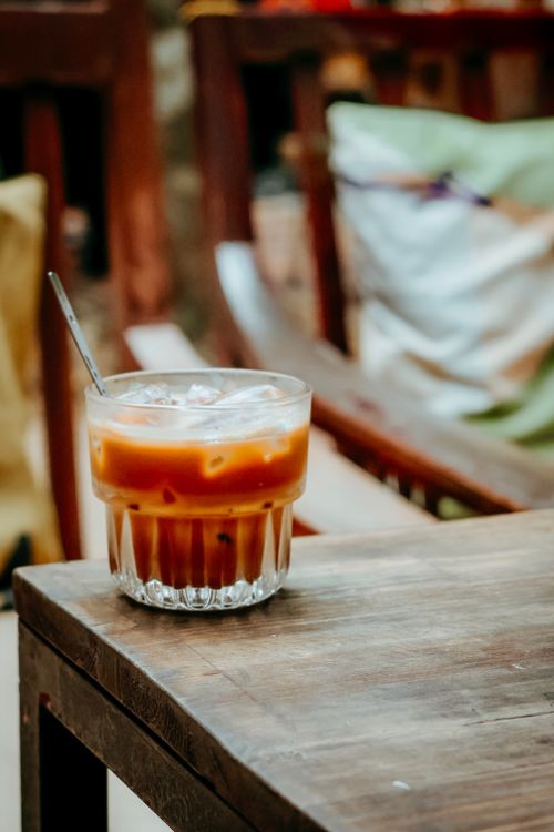 Free Chilled iced coffee served in a glass with straw on a cozy outdoor setting. Stock Photo