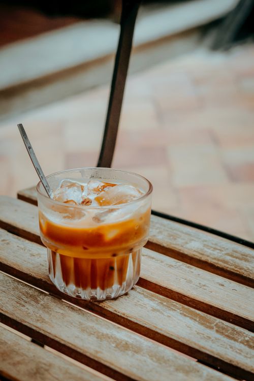 Free Refreshing iced coffee served on a rustic wooden table outside. Stock Photo