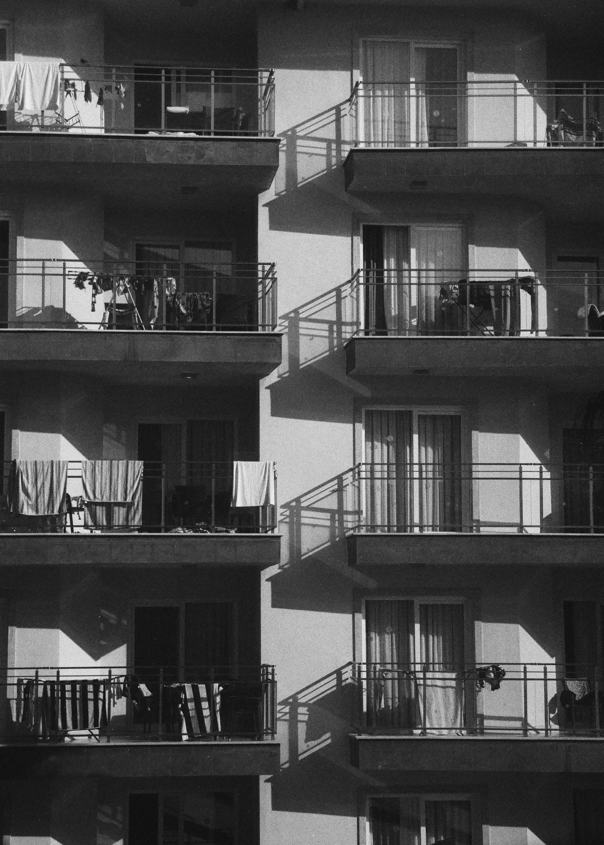 Monochrome image of an urban apartment building with balconies and shadows.