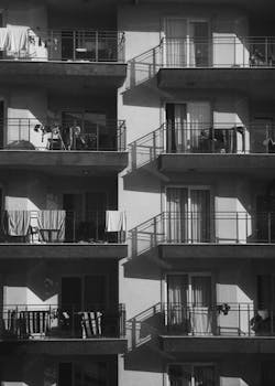 Monochrome image of an urban apartment building with balconies and shadows.