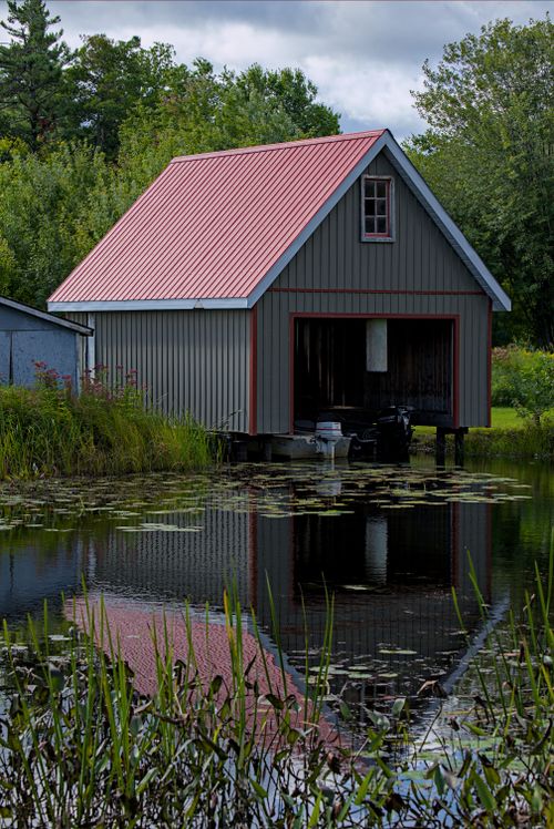 Free A charming boathouse with red roof reflecting in a tranquil marsh in Ontario, Canada. Stock Photo