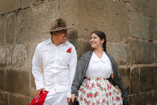 Smiling couple in traditional attire enjoying a sunny day in Oaxaca City, Mexico.