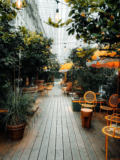 Free A cozy outdoor cafe setting surrounded by greenery and yellow umbrellas, ideal for relaxation. Stock Photo