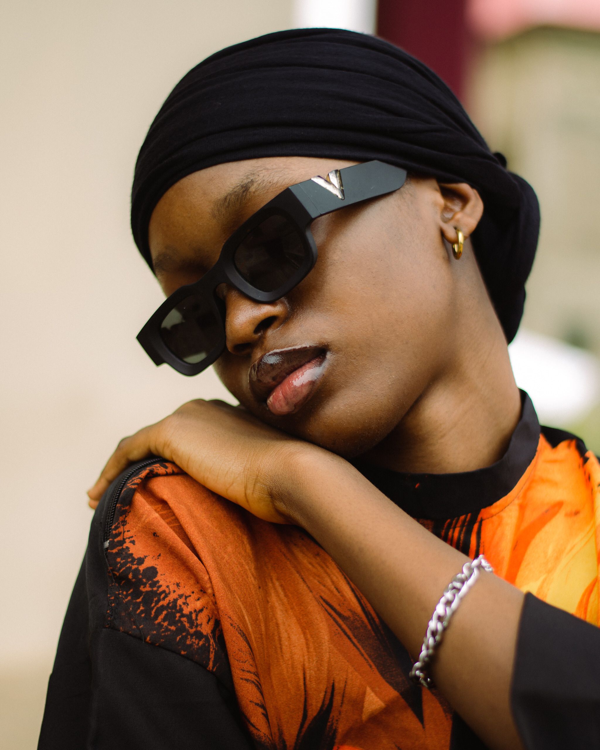 Woman in sunglasses and hijab posing elegantly, showcasing fashion and style.