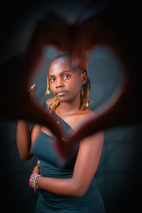 Free A creative portrait of a woman framed by a heart shape made with hands, symbolizing love. Stock Photo
