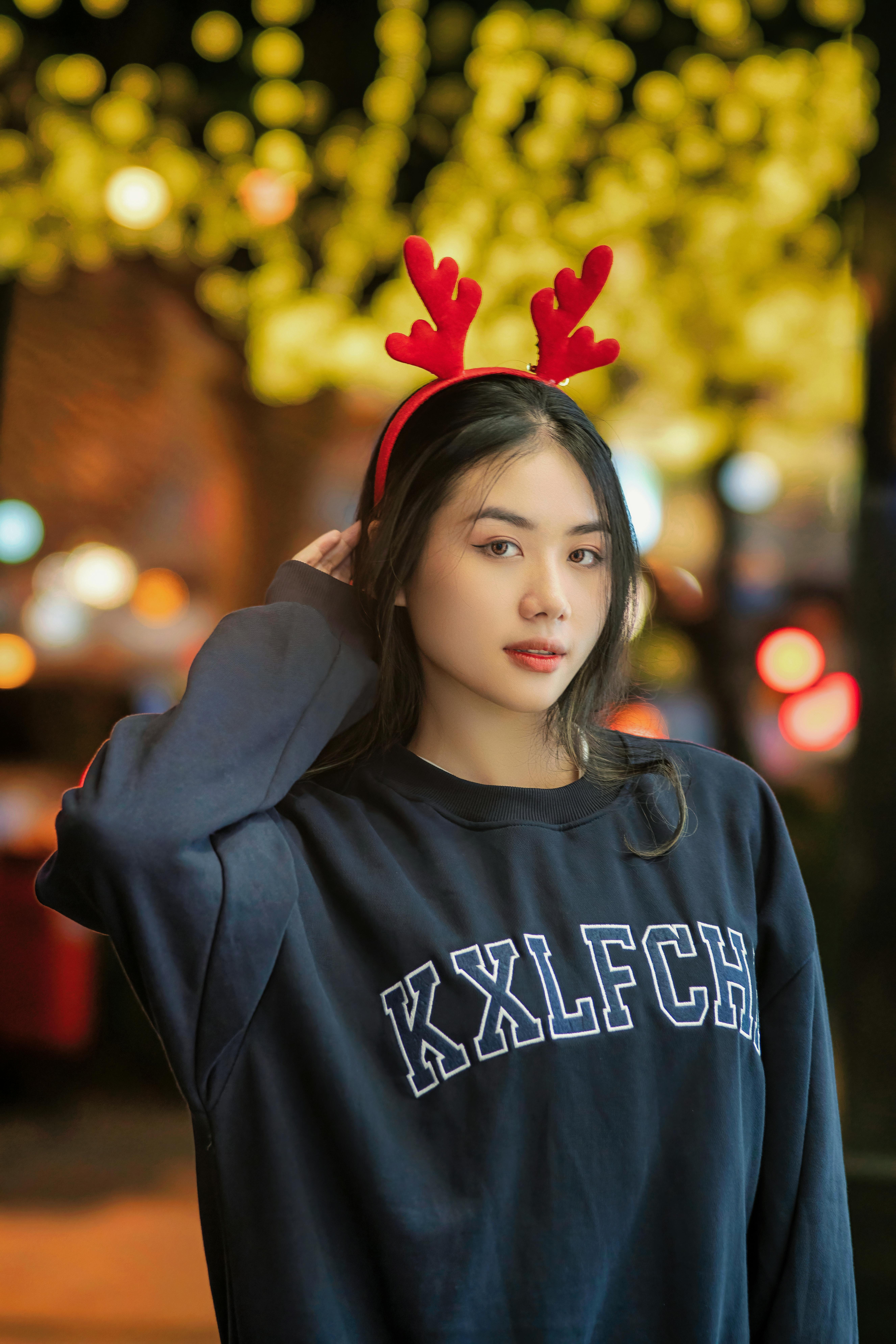 De franc Retrat d'una dona jove amb una diadema de banyes de ren a la nit durant la temporada festiva. Foto d'estoc