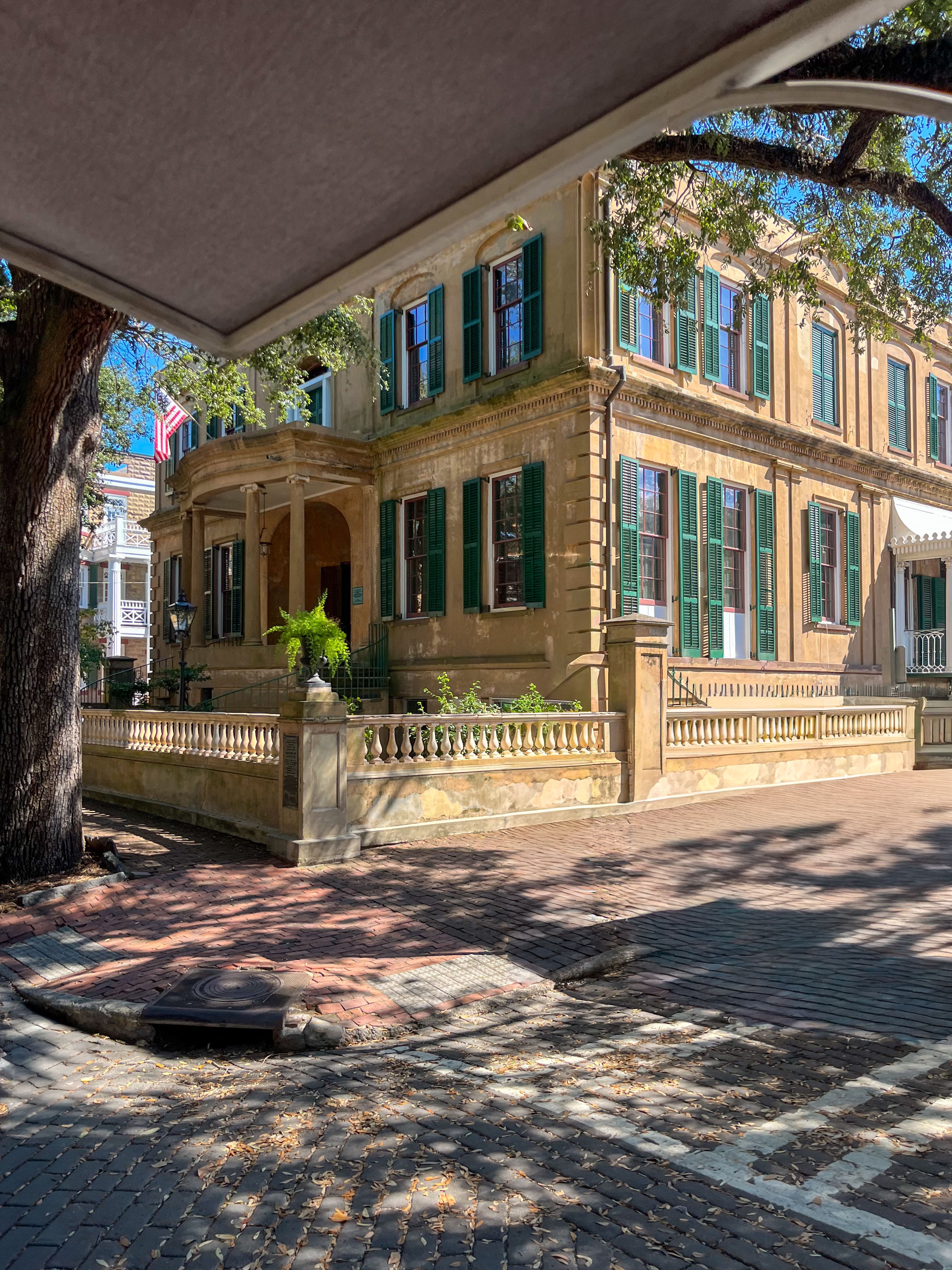 Elegant historic mansion with green shutters under clear blue sky.