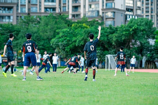 Teenagers playing soccer in a city park, surrounded by urban apartment buildings.
