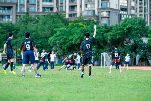 Free Teenagers playing soccer in a city park, surrounded by urban apartment buildings. Stock Photo