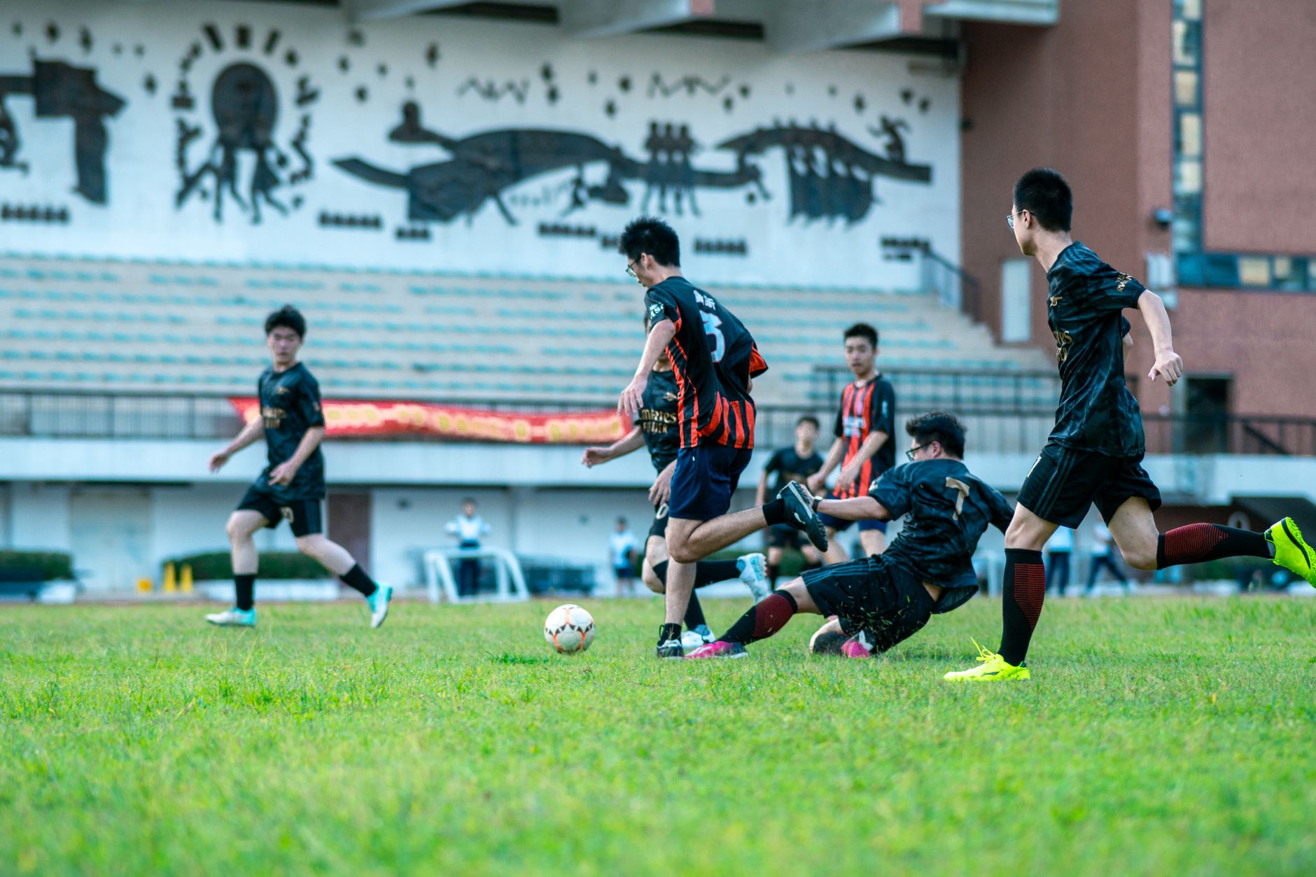 teenage football players performing supervised landing drills beside cones on an outdoor academy pitch