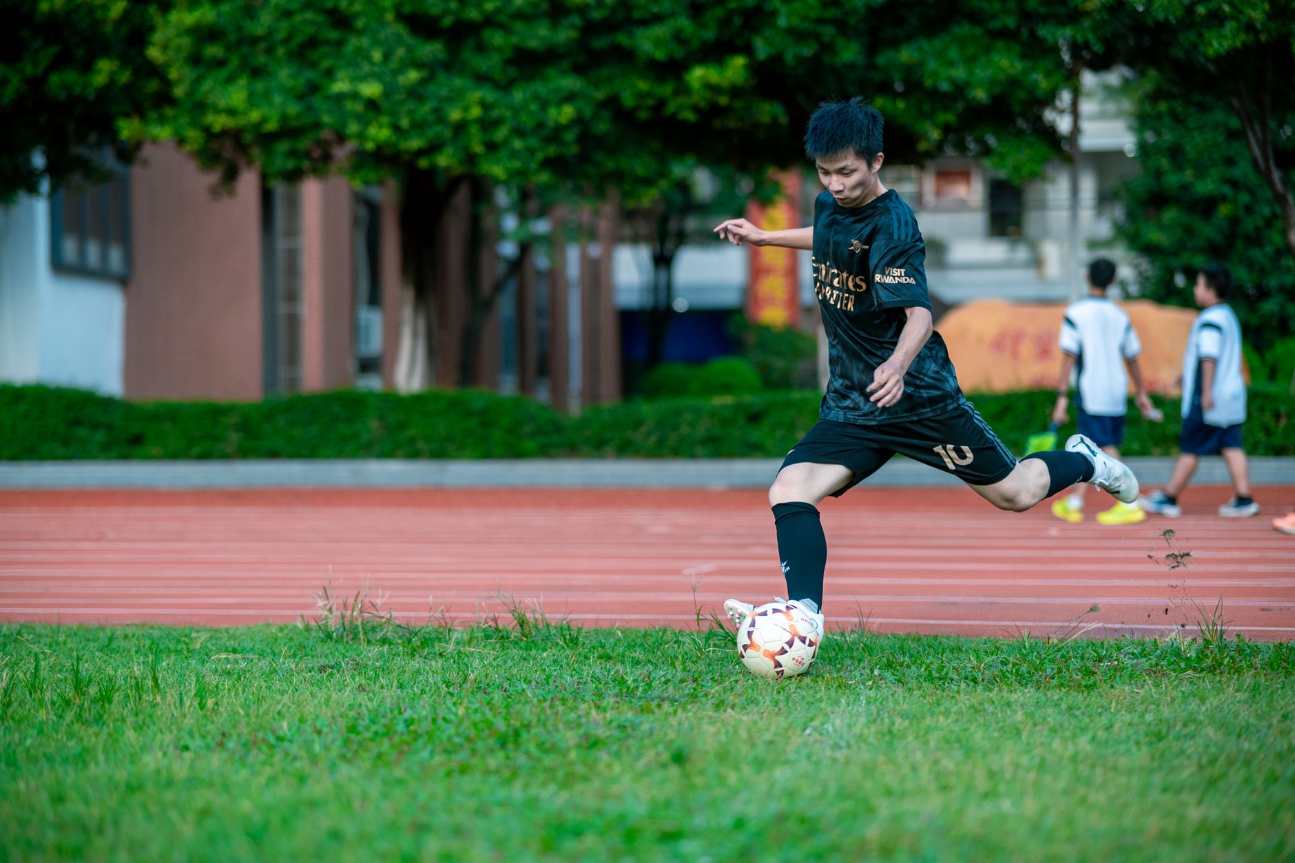 Action shot of a teenager skillfully kicking a soccer ball outdoors during daytime.