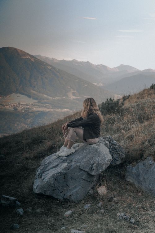 Free A serene scene of a woman sitting on a rock overlooking the stunning Alpine landscape near Innsbruck, Austria. Stock Photo