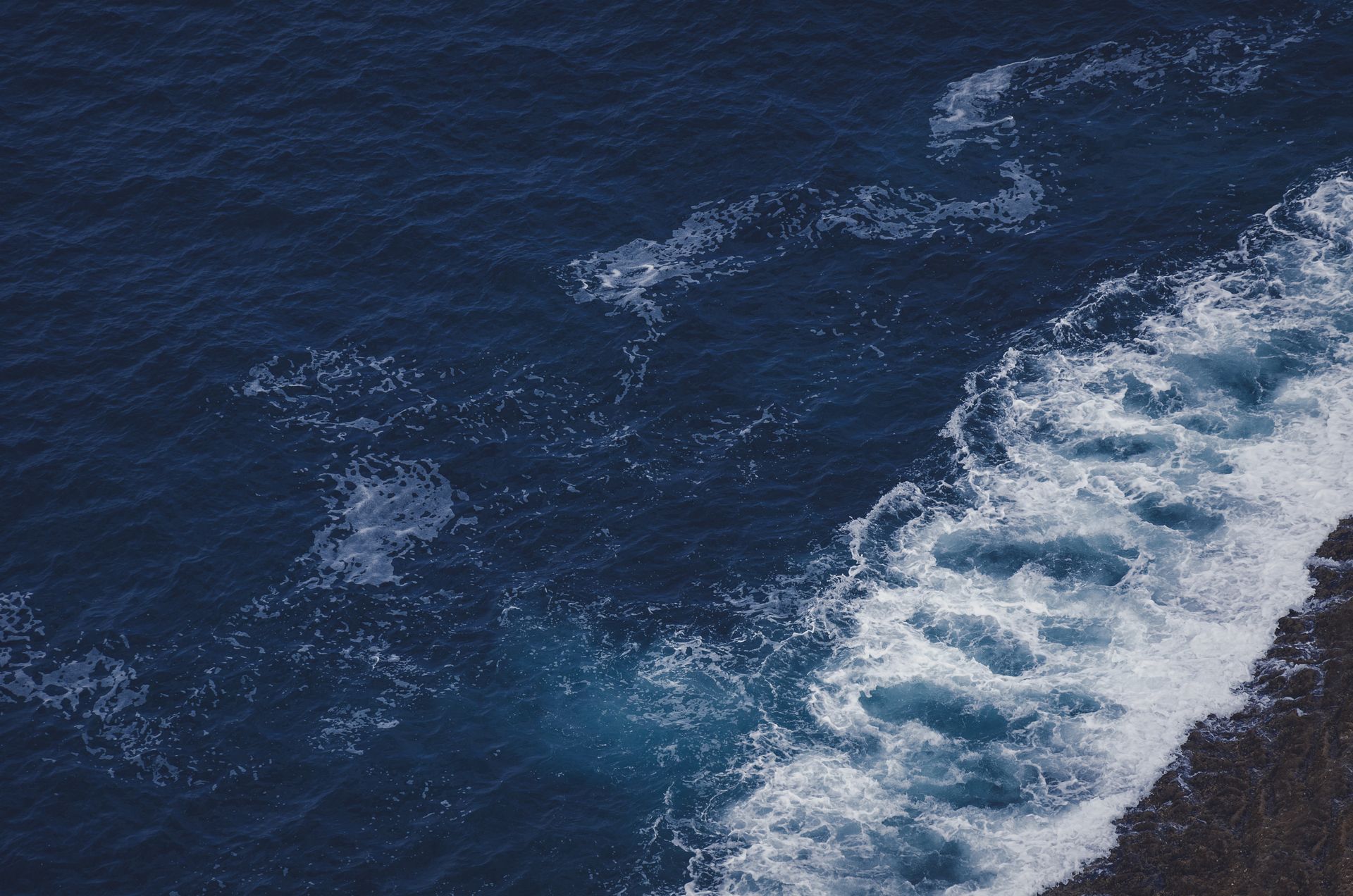 Waves crash gently on rocky coastline creating a serene ocean scene at sunrise
