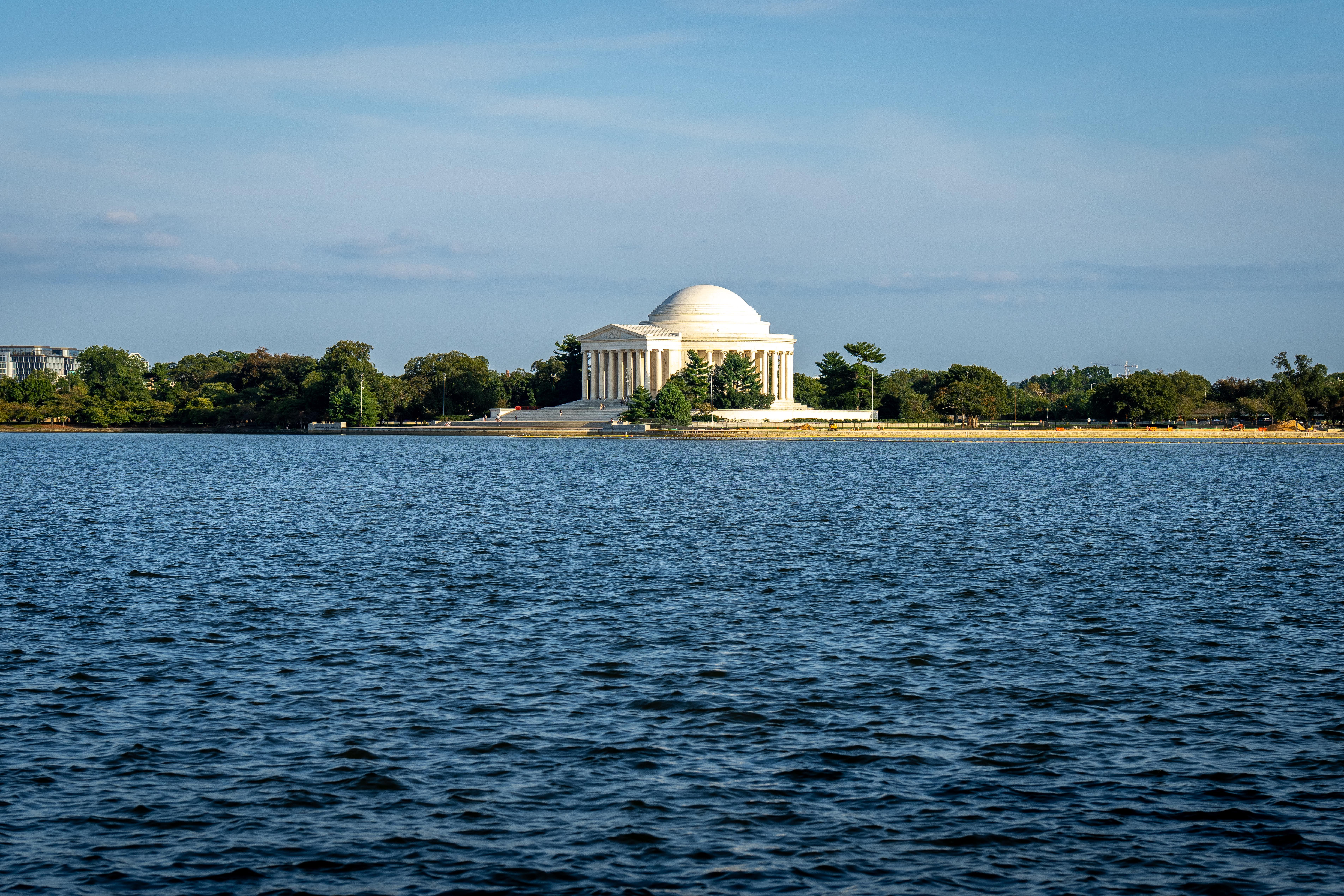 A serene view of the Jefferson Memorial with a clear blue sky and water reflecting its grandeur.
