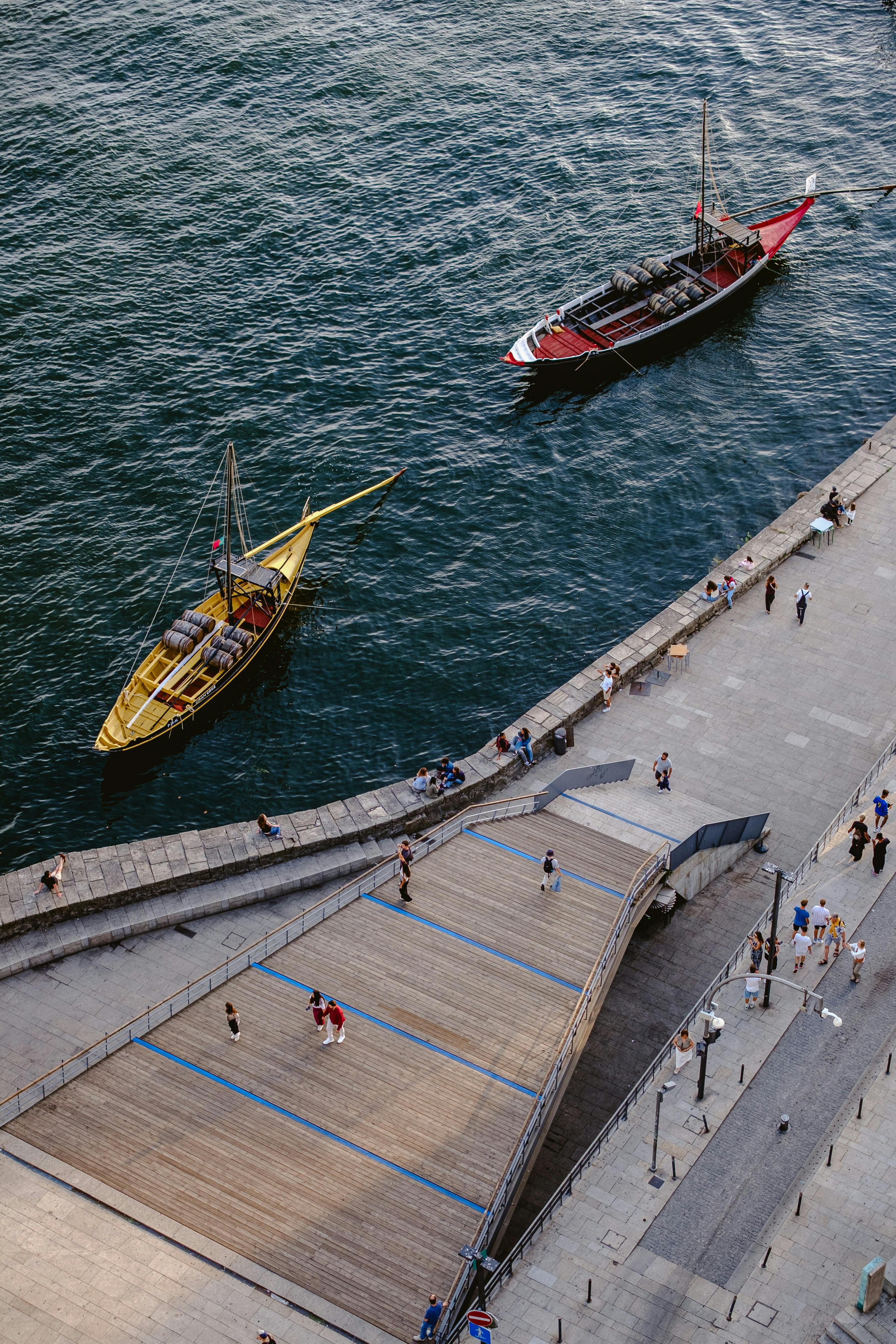 Aerial view of a waterfront with people walking and boats floating. Summer setting with a bright mood.