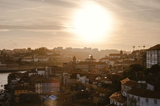 Golden sunset casting a warm glow over Porto, Portugal's historic cityscape with iconic architecture.