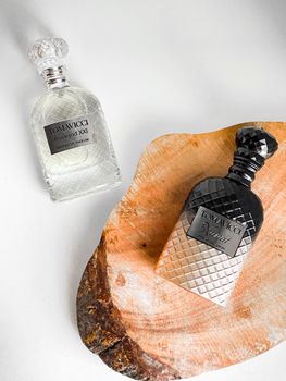 Two luxurious perfume bottles on wooden slab showcasing elegance and style.