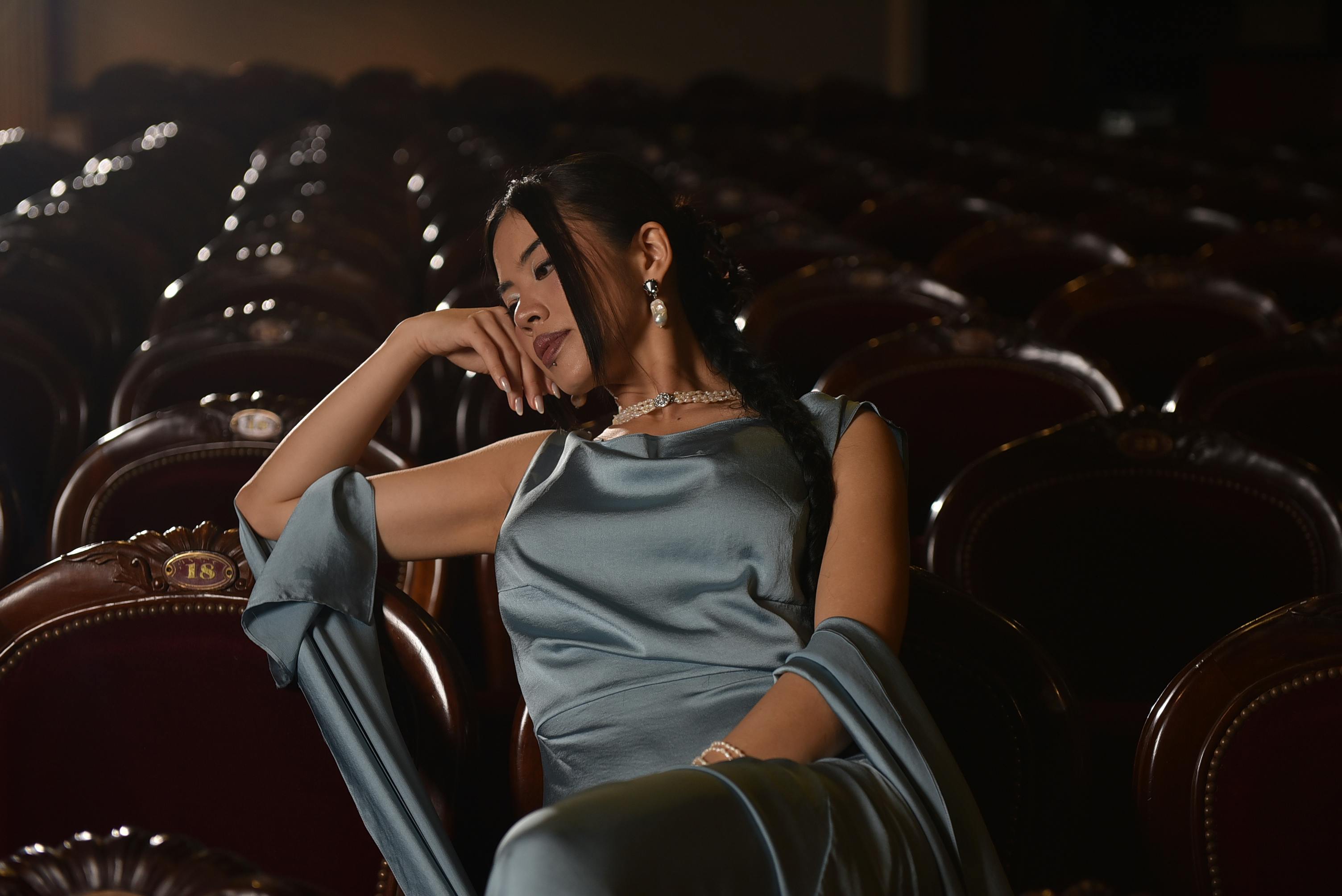Free Woman in blue evening gown sitting elegantly in a theater auditorium. Stock Photo
