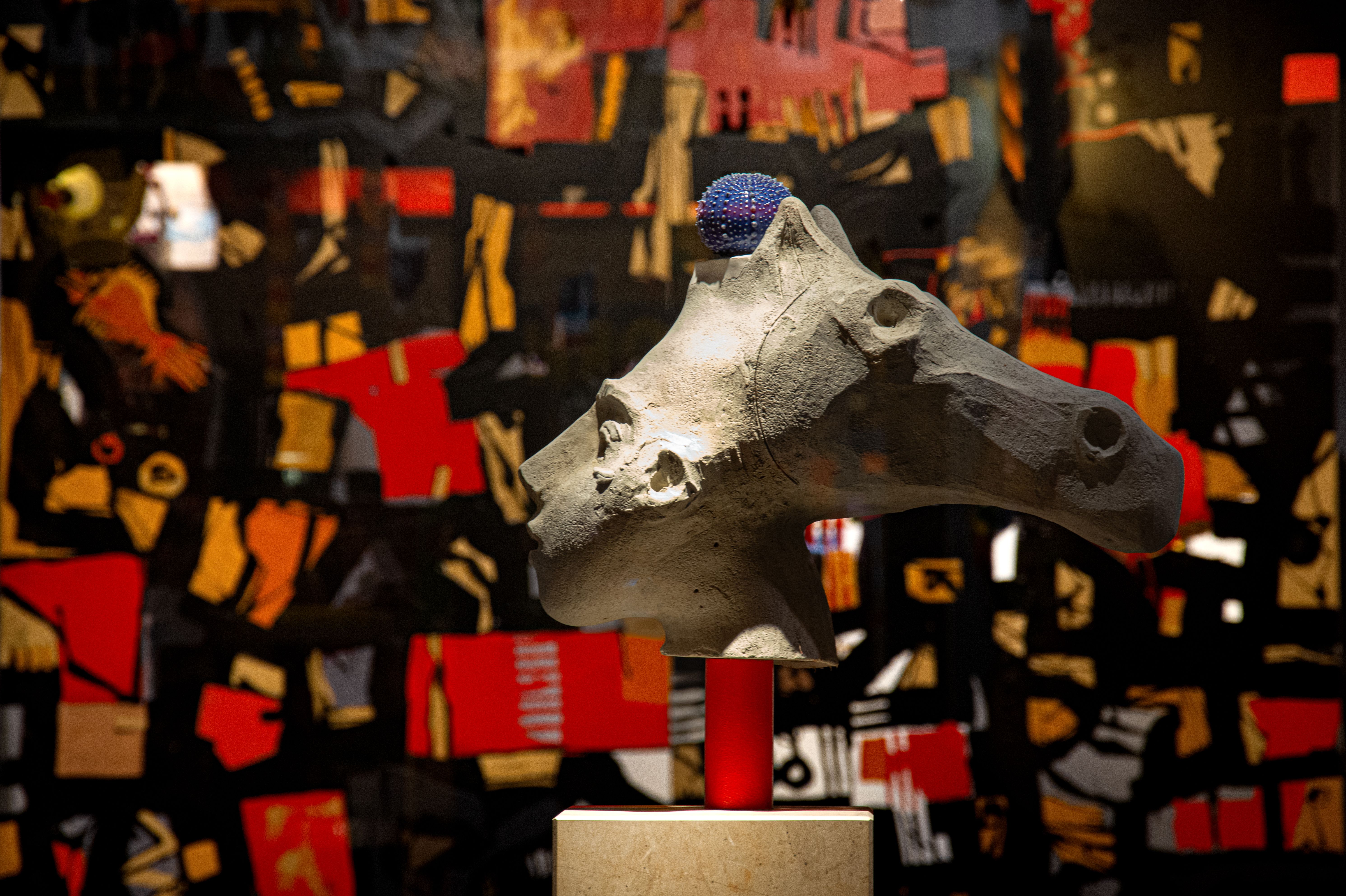 Free Stone horse sculpture in an abstract art exhibit with colorful backdrop. Stock Photo