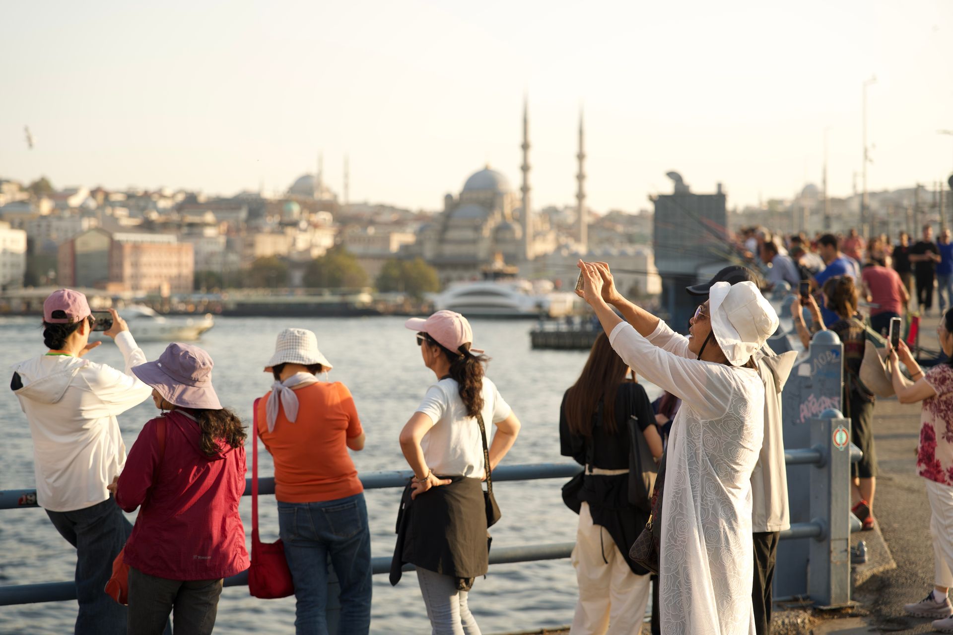 Tourists capturing the scenic view of Istanbul with historic landmarks under the sunny sky.