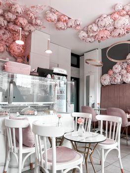 Beautifully decorated cafe with pink flowers and elegant white furniture, perfect for a serene experience.