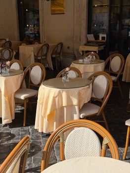 Charming outdoor cafe featuring cozy tables with flower vases, perfect for a sunny day.