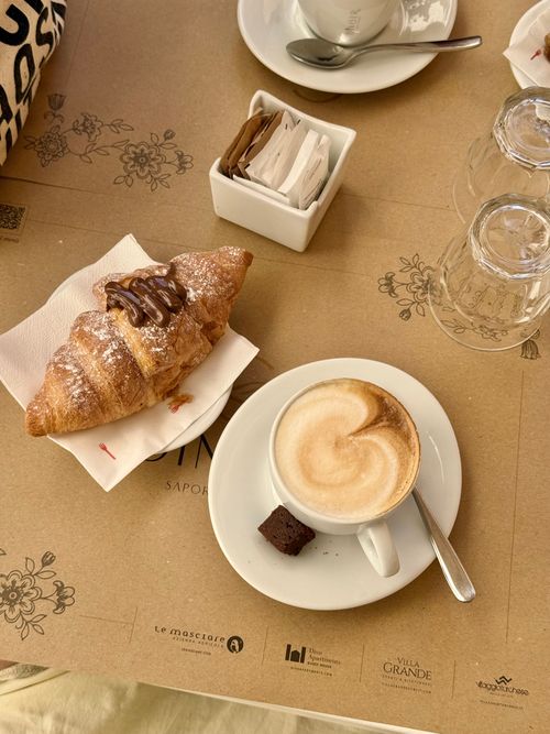 Free Cozy morning setup with cappuccino and chocolate croissant, perfect start to the day. Stock Photo