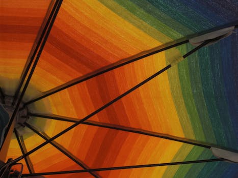 Colorful close-up of a rainbow beach umbrella viewed from below, capturing vibrant summer vibes.