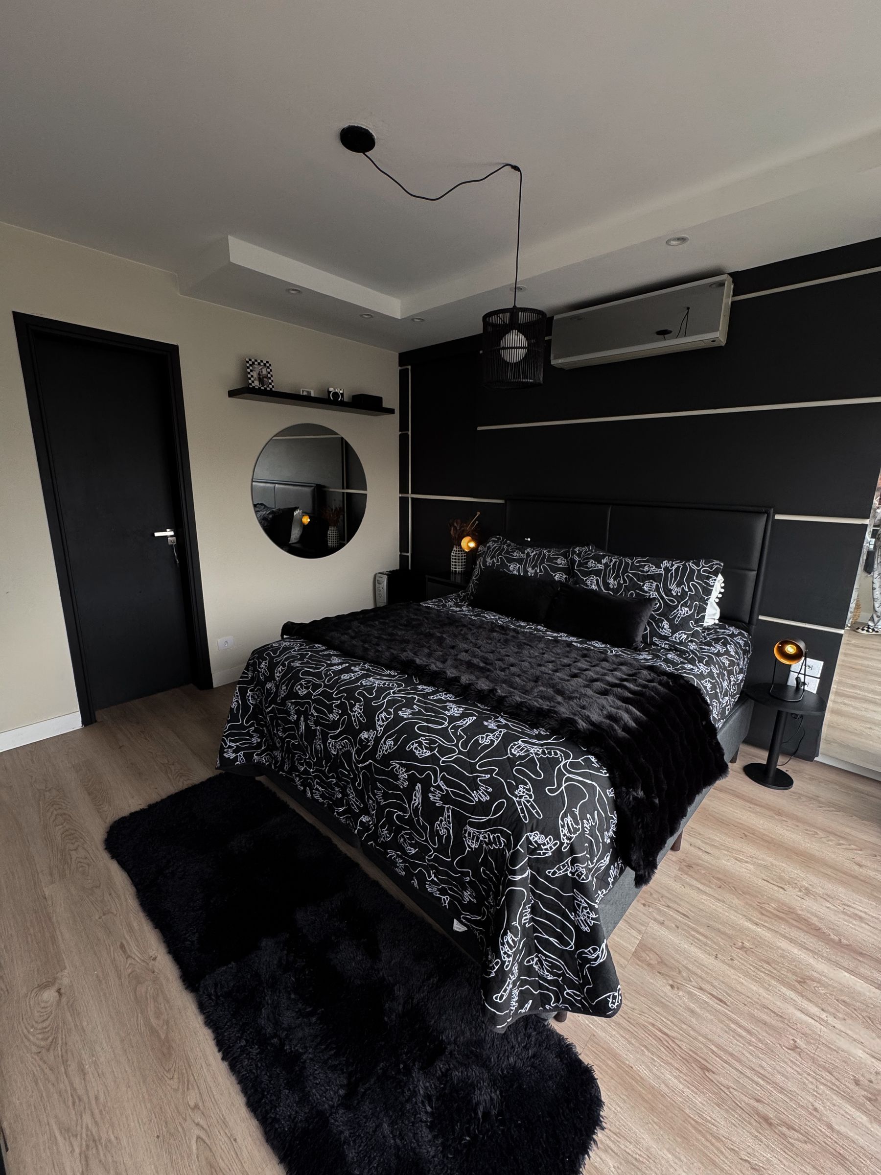 Black-led modern bedroom with dark walls, pale bed, plants and warm bedside light