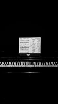 Classic black and white image of a piano with sheet music, creating a moody and artistic ambiance.