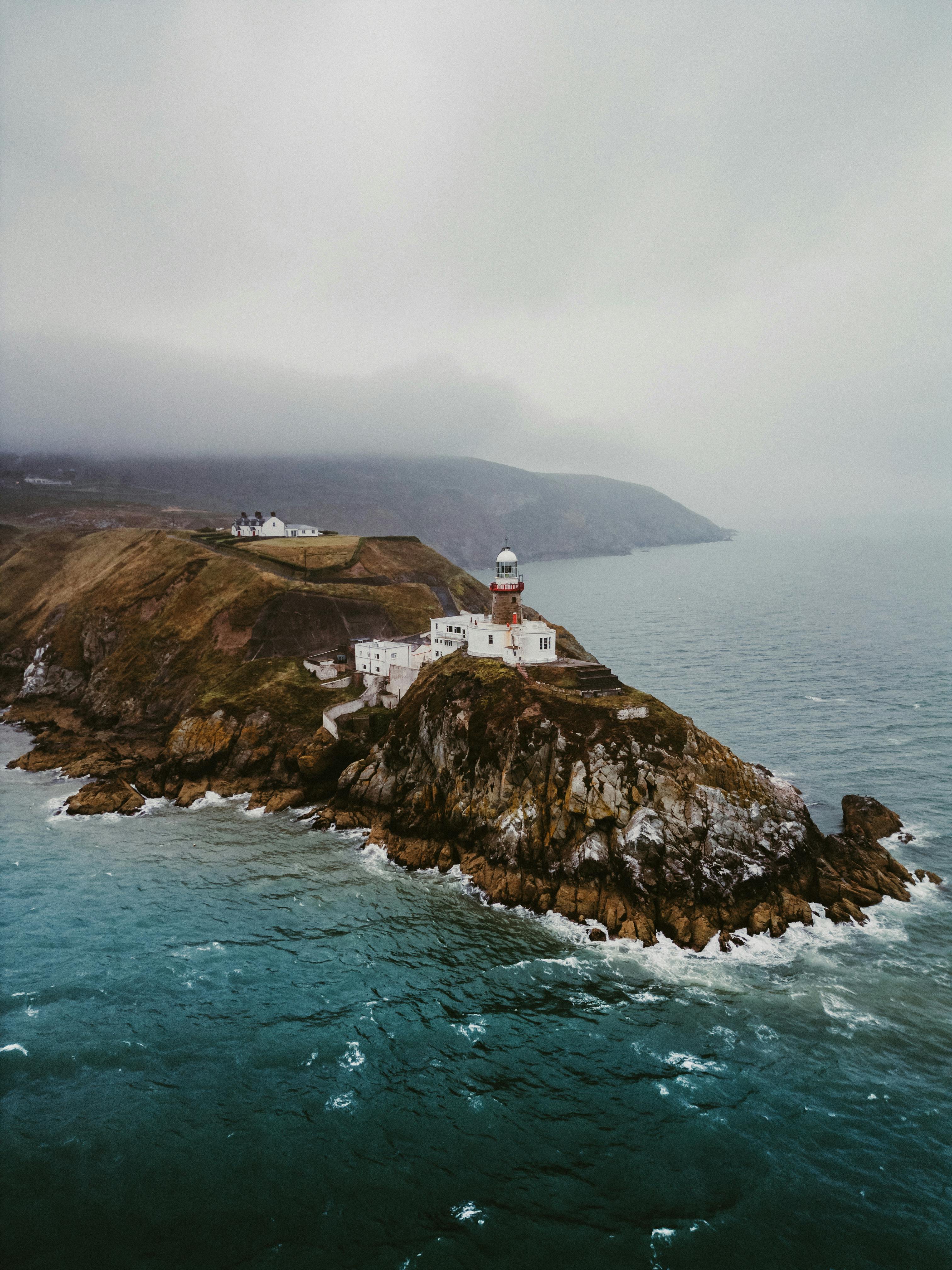 Aerial view of Howth Lighthouse on a rocky cliff, surrounded by the sea, Dublin, Ireland.