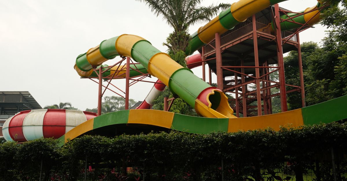 Brightly colored water slide with green, red, and yellow sections at a waterpark in East Java.