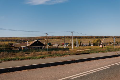 Free Tranquil rural landscape with fields and power lines under a clear blue sky. Stock Photo