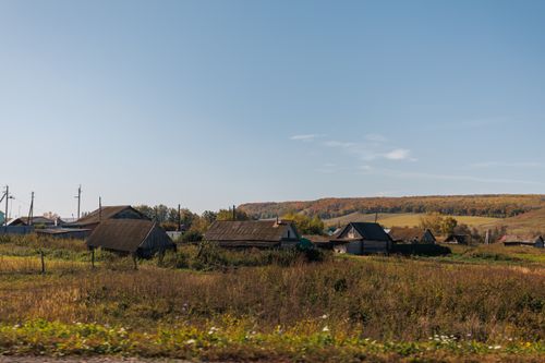 Free Autumn view of a quaint rural village with wooden houses under a clear blue sky. Stock Photo