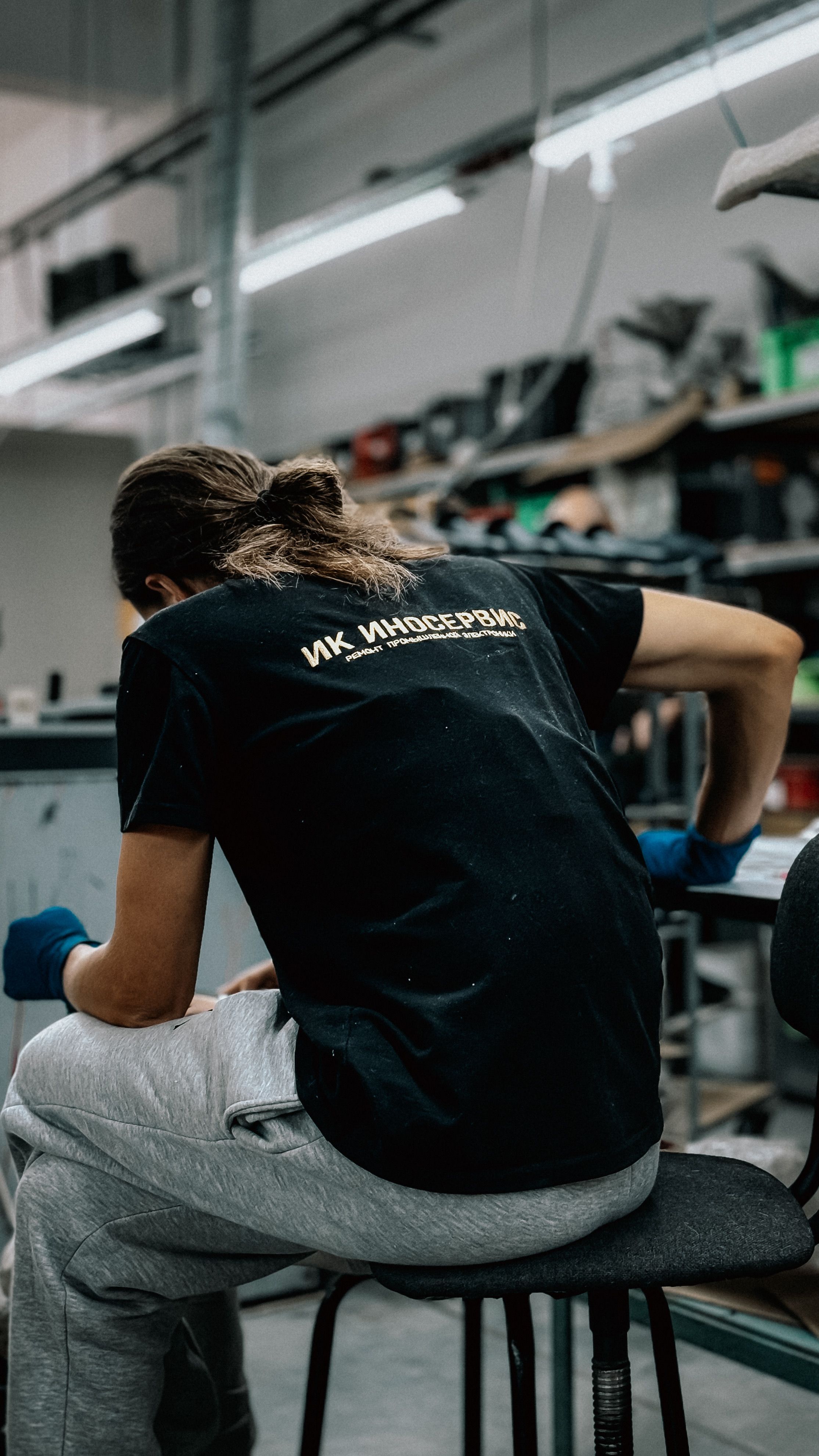 A young man focused on work in a busy industrial workshop environment.