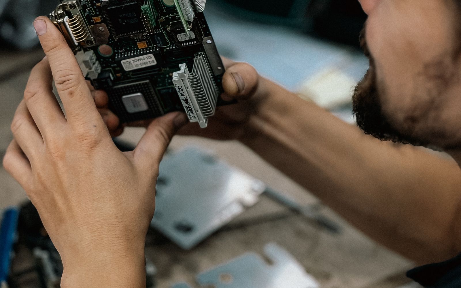 Technician examining a circuit board in a workshop; illustrative photograph rather than a Zuken software demonstration
