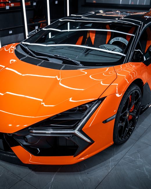 A stunning orange sports car showcased in an Ankara, Türkiye showroom, highlighting sleek design and luxury.
