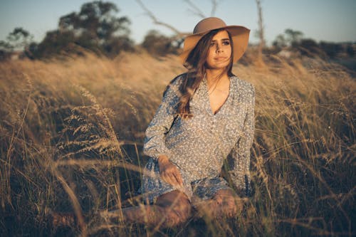 A Woman in Gray Long Sleeve Dress Sitting on the Field