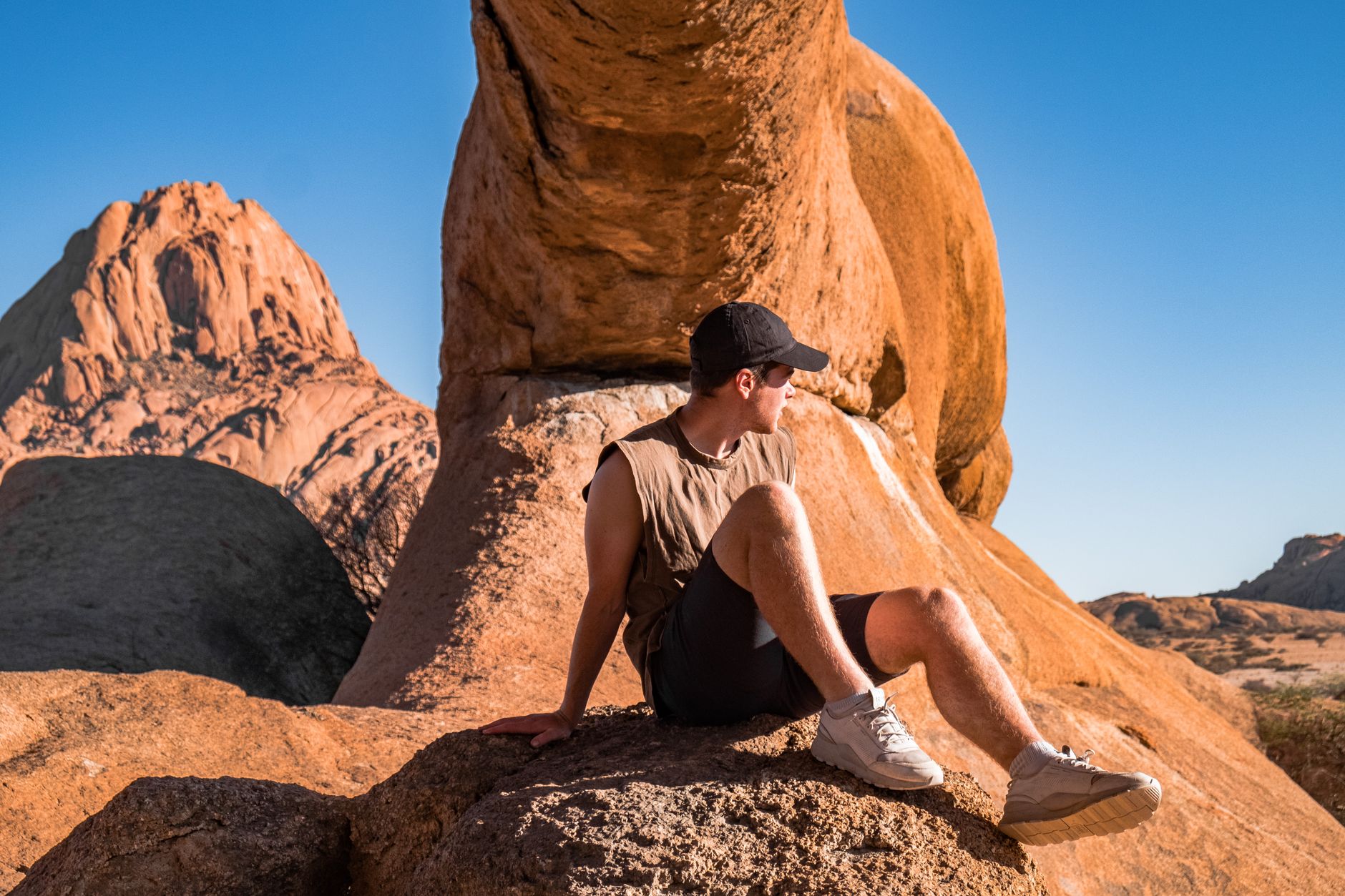 A man relaxes on sunlit rocks at Spitzkoppe, Namibia's striking mountain range.