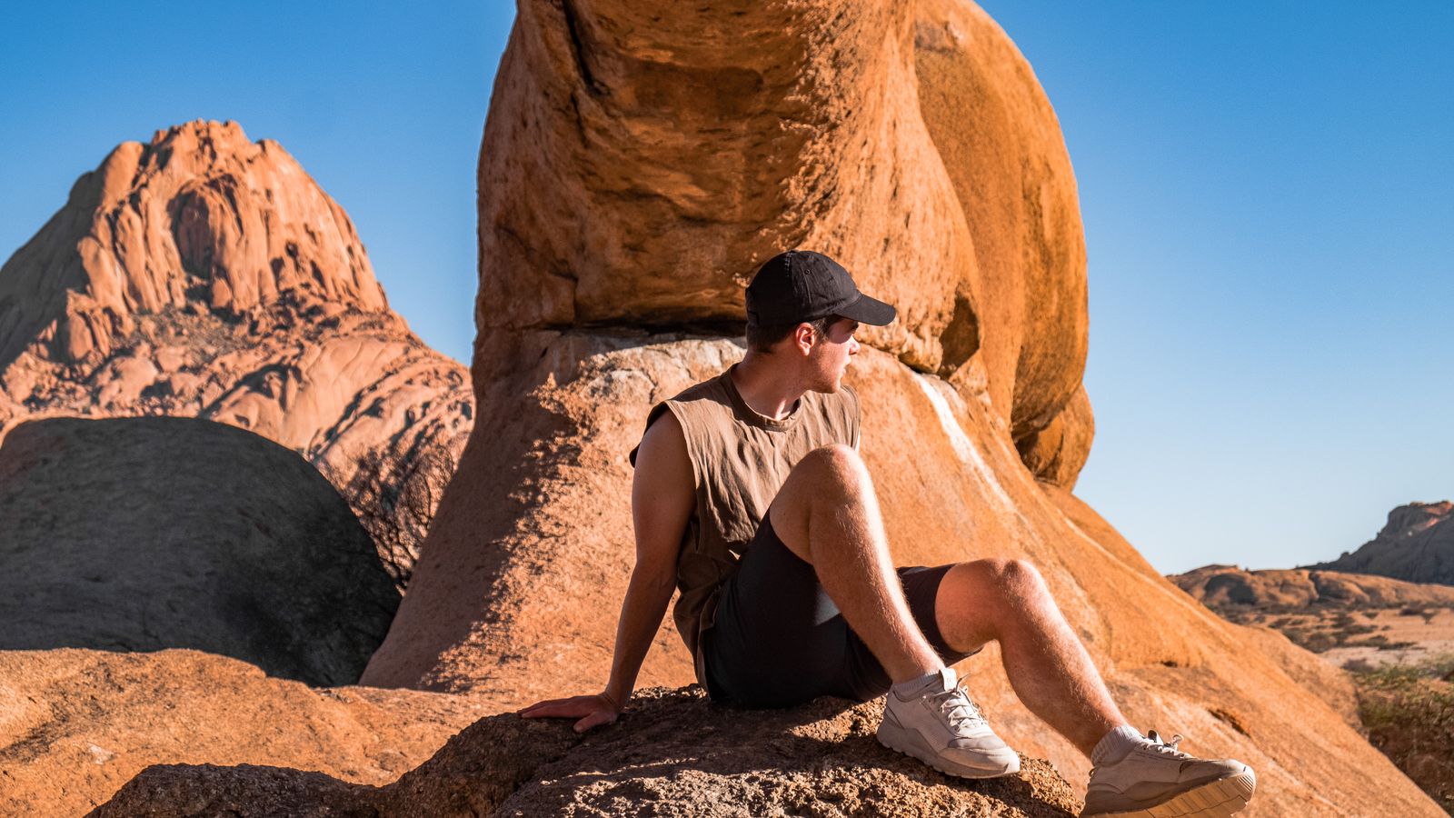 Man sitting under barren rocks, Namibia