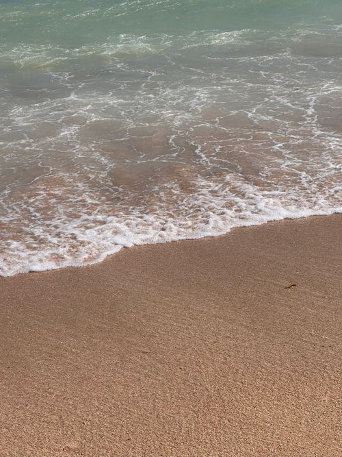 Free Gentle ocean waves lapping onto a sandy beach, creating a calming coastal scene. Stock Photo