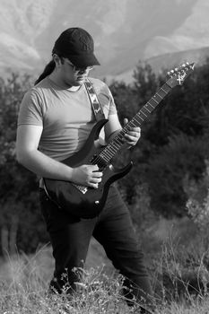 Passionate young musician playing electric guitar in natural setting of Qazvin, Iran.