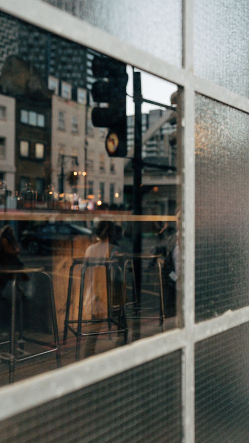 Free Cityscape reflection through cafe window showcasing urban life and architecture. Stock Photo