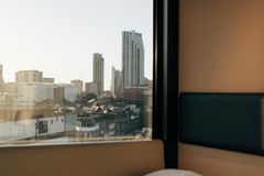 Urban skyline view through hotel window at dawn, cozy ambiance.