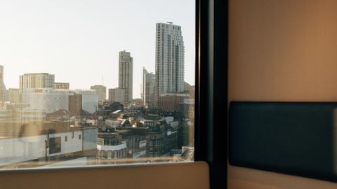 Urban skyline view through hotel window at dawn, cozy ambiance.