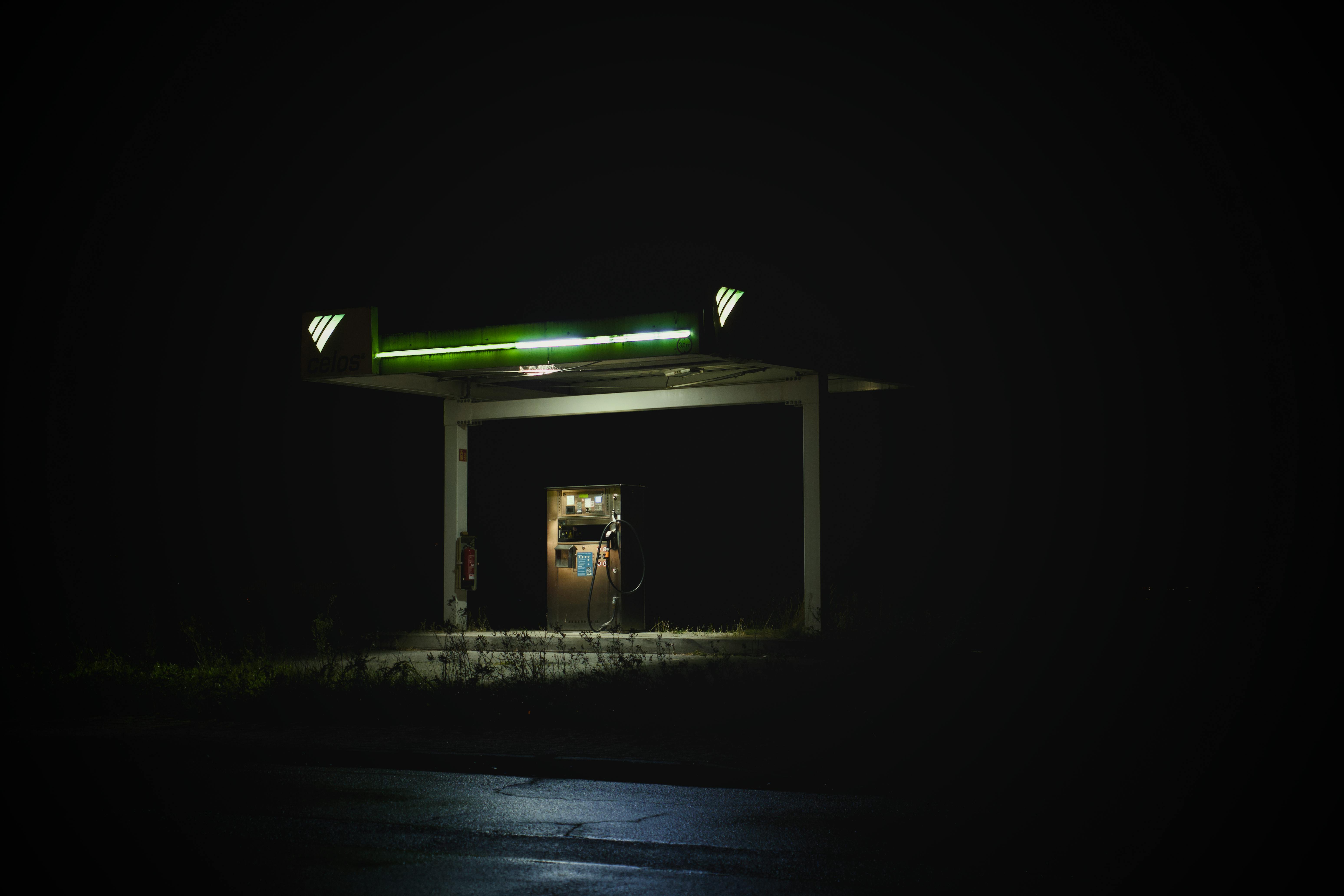 Gratis Isoleret tankstation, der lyser om natten mod en mørk baggrund og skaber en mystisk stemning. Lagerfoto