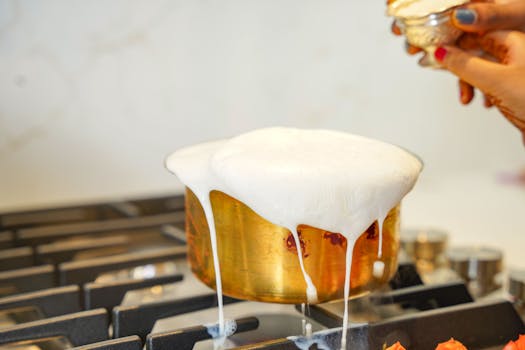 Golden pot overflowing with milk on a stove, captured in a warm kitchen setting.