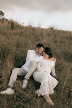 A romantic moment captured of a couple embracing in a serene grass field.