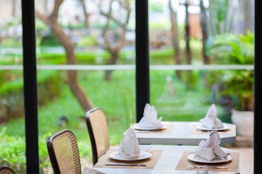 A sophisticated restaurant table setup by a window overlooking a lush garden view.