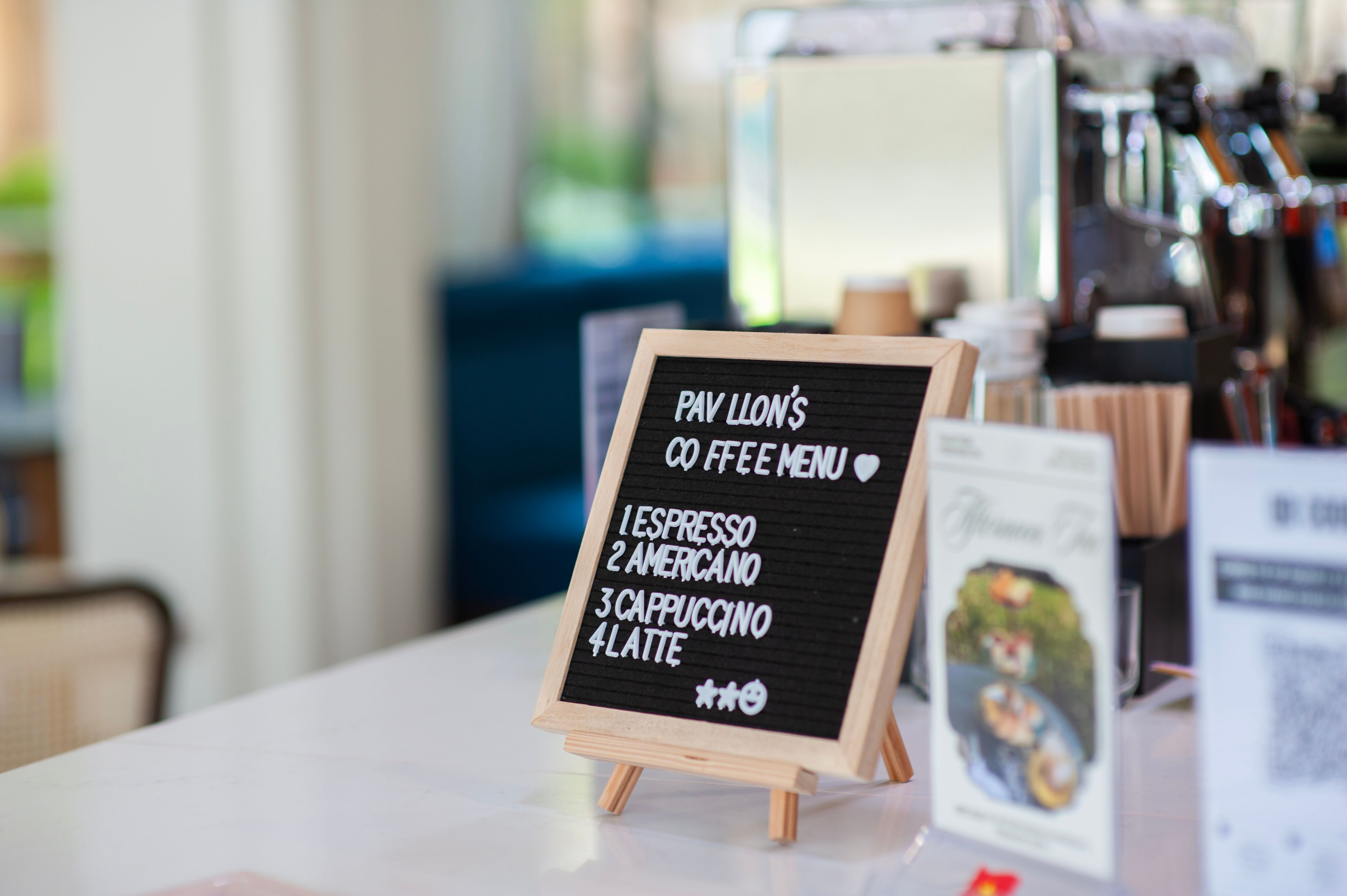 A wooden menu board in a coffee shop displaying espresso varieties like Americano and Latte.